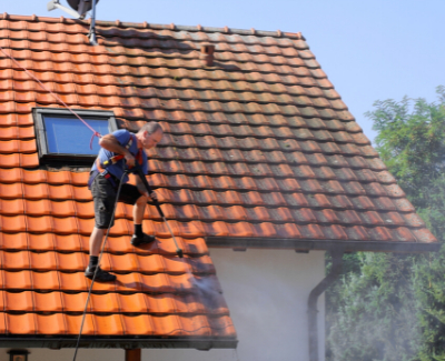 Roofing-Johnson-City-Taking Care of Your Roof: The Benefits of Keeping Your Roof Clean - man on tiled roof cleaning out debris