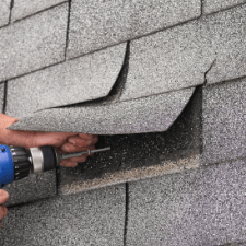 roofing bristol tn - 5 Things That Will Not Protect Your Roof - hands holding a drill and driving screw onto shingled roof