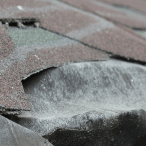 emergency roof repair near me - a damaged roof where asphalt shingles are tattered while some are missing